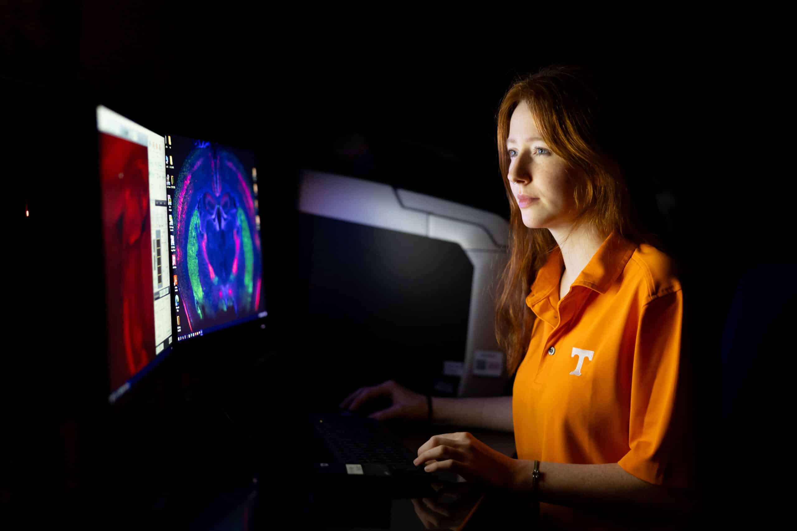 Madison Gossard, a postbac trainee, examines stained tissue using an epifluorescent microscope.